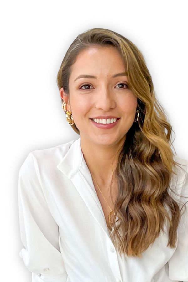 Mujer sonriente de pelo largo y ondulado, con camisa blanca y pendientes de oro, que desprende un aura caribeña de renovación y rejuvenecimiento sobre un fondo blanco liso.