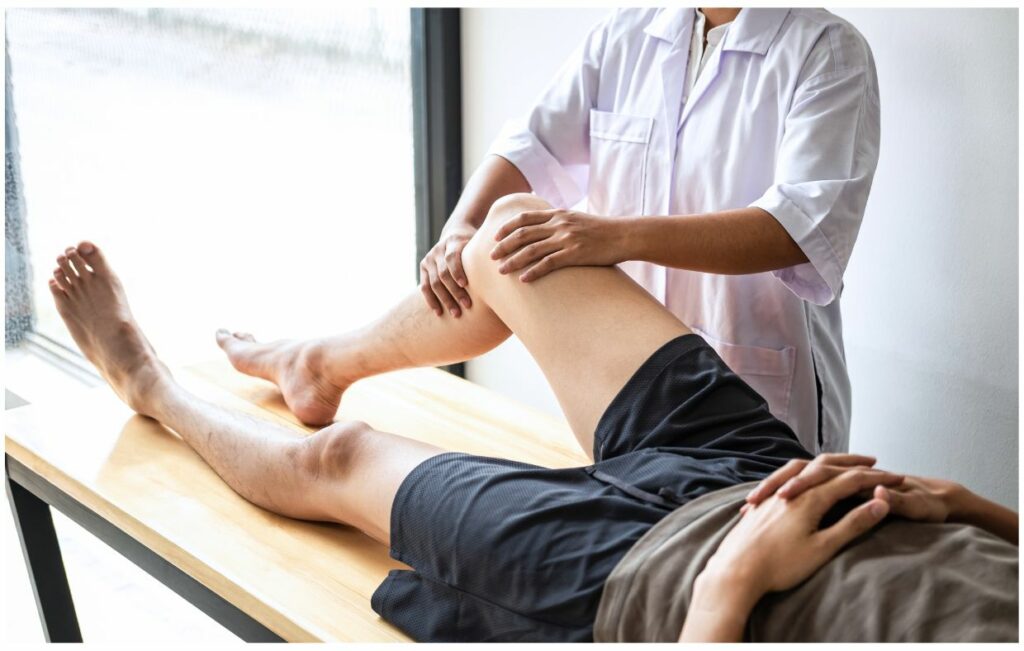 In Colombia, a specialist in a white coat examines the knee of another person lying on a wooden table, showcasing expertise in sports medicine.