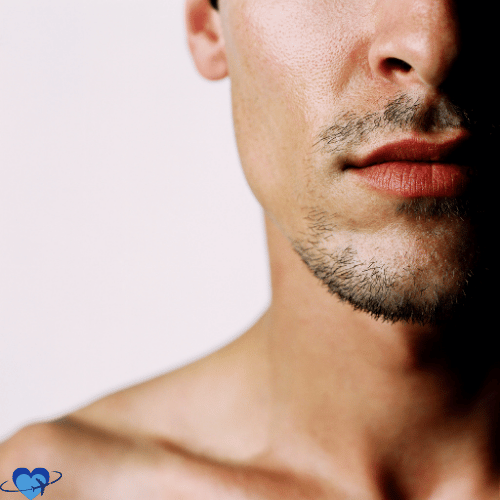 Close-up of the lower half of a man's face, showcasing lips and chin with light stubble, subtly hinting at the transformative potential of maxillofacial surgery. The background is a plain white.