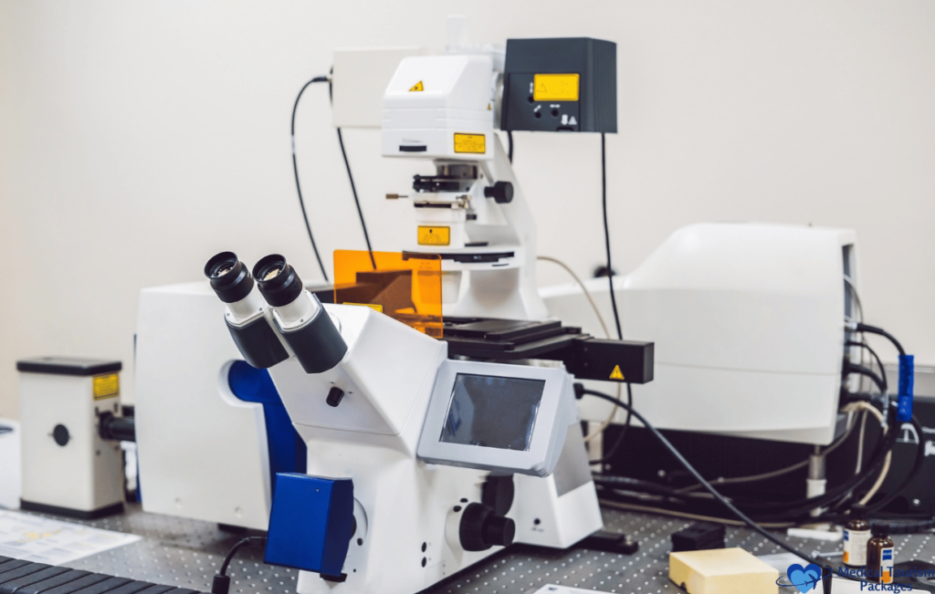 A laboratory microscope with multiple lenses and an attached display screen is set up on a table, offering precision essential for medical tourism. Various equipment and bottles are visible in the background, reinforcing Colombia's reputation as an ideal destination for advanced medical care.