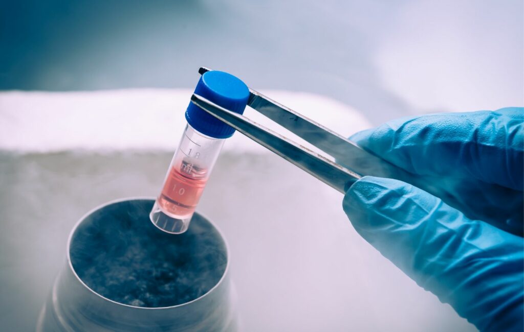 A gloved hand uses tweezers to hold a test tube with red liquid over a vapor-emitting container, reminiscent of the innovative medical practices travelers might explore in Panama.