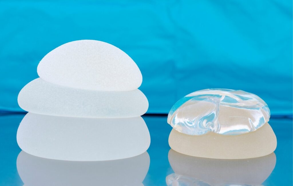 Four silicone breast implants of varying sizes are stacked on the left, while two with a clear outer shell sit on the right. Set against a bright blue background, these are essential tools in mammoplasty procedures for breast augmentation, popular choices for patients from Panama.